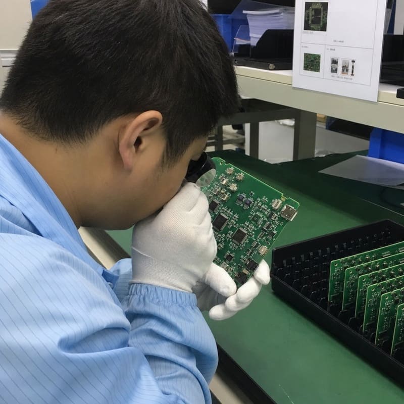 Quality control operator performing manual visual inspection on a high-density PCBA board – Fuxin PCBA