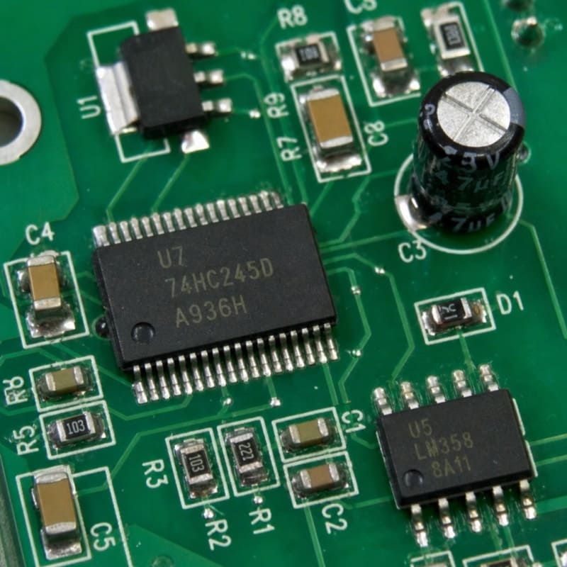 Close-up of an assembled PCBA board featuring 74HC245D SMT IC and through-hole electrolytic capacitor – Fuxin PCBA